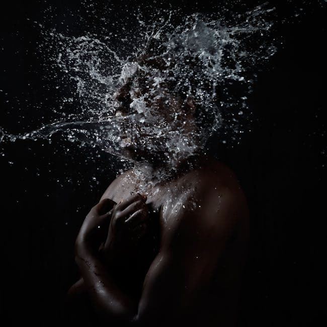 Artistic studio shot of water splashing on a person, creating a dynamic and dramatic effect.